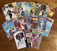 Photo of 20 assorted used comic books laid out on a wooden surface, showing colorful covers and various superhero and fantasy themes.