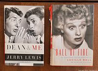 Two hardcover books side by side. Left is "Dean & Me" by Jerry Lewis and Dean Martin; right is "Ball of Fire" by Lucille Ball with visible damage to the dust jacket spine.