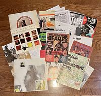 Top view showing assortment of Beatles magazines, booklets, and prints spread on wooden floor