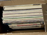 Top-down view of box containing stacked vintage vinyl record sleeves and records