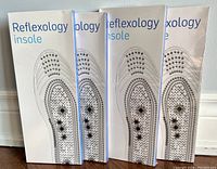 Four packages of reflexology insoles standing side by side, showing front with printed acupoints design and text 'Reflexology insole'
