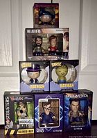 Collection of boxed vinyl figures stacked, including The Last of Us set, South Park Cartman, Dorbz Batman figures, and boxed Ghostbusters, Doctor Who, and Uncharted figures.