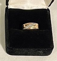 Front view of the ring in black velvet presentation box showing gold band and diamond channel.