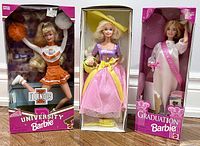 Three boxed Barbie dolls displayed side by side showing full packaging and figure details