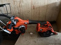 Photo of the Black & Decker 20V leaf blower and cordless circular saw placed on a floor against a wall, showing condition and included battery on leaf blower.