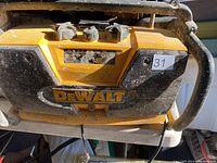 Front view of DeWalt portable radio with visible dirt, control knobs, and metal protective frame.