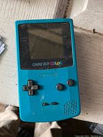 Front view of a blue Nintendo Game Boy Color handheld console, showing screen, buttons, and speaker