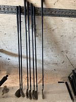 Full view of 7 Titleist Trispec irons standing vertically showing the club heads and shafts.