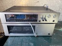 Stacked Luxman FM stereo tuner on Luxman stereo power amplifier showing front panels, controls, analog display and VU meters