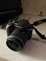 Front-angle view of camera body mounted with kit lens and attached Nikon strap