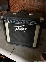 Front view of the amplifier showing control panel, handle, and logo on speaker grille.