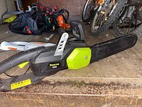 Side view of Poulan Rhetoric chainsaw showing the black and green body, handle, long bar with cover, and Poulan branding.