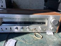 Front view of the Technics stereo receiver showing the tuning window, control knobs, and wood side panel.