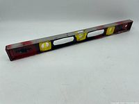 Full view of the vintage contractor's level showing its length, red ends, and the three yellow bubble vials spaced on the black metal body