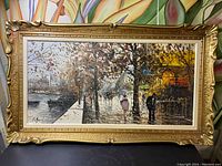 Full view of the framed painting showing the Paris street scene with wet trees and figures, signature visible lower left.