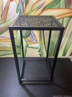 Front view of a black steel planter stand with square frame and circular perforated top, showing overall structure and design.