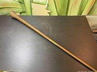 Full length image of the vintage copper trumpet lying on a dark surface showing its straight and slender form.