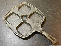 Top-down view of vintage cast iron skillet showing four square cooking compartments and small central compartment.