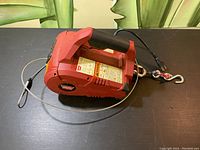 Side view of entire winch on table showing handle, housing, cable and power cord