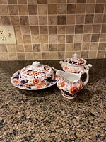 Covered butter dish, sugar bowl with lid, and creamer arranged on kitchen counter to show pattern and condition.