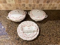 Full set of MZ Altrohlau Bridal Rose china including lidded vegetable dishes and plates on granite countertop.