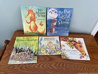 Overview of all five children's books arranged on a wooden surface.
