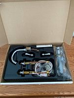 Box opened showing all faucet components organized neatly in a molded plastic tray with the brand Delta embossed.