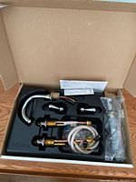 Delta chrome bathroom faucet components neatly organized in a black plastic tray inside an open box, showing spout, handles, hoses, and instruction manual.