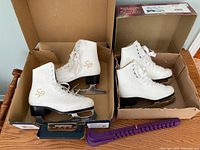 Pair of white SP figure skates, size 6 and size 2, in open boxes showing condition and branding