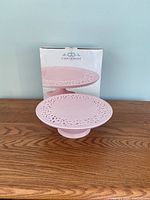 Casa Domani pink footed cake stand with original packaging visible behind it, showing front and side angles.