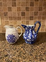 Wide shot of both pitchers side by side on granite counter with tiled backsplash.