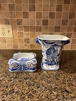 Front view of the monkey vase and the trivet side by side on a countertop, showing detailed blue and white porcelain work.
