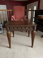 Front and leg detail view of the wood side table showing the carved apron detail and fluted legs.