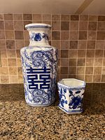 Photo showing the blue and white ceramic vase alongside the hexagon plant pot on a granite countertop with tiled backsplash.