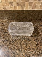Photo showing the vintage glass refrigerator food storage box closed with lid, highlighting the ribbed textured sides and detailed lid design.