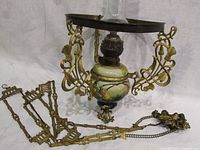 Antique hanging oil lamp showing hand-painted glass reservoir with floral design and ornate brass frame.