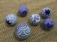 Six blue and white ceramic carpet balls arranged on a textured brown carpet showing various intricate patterns.