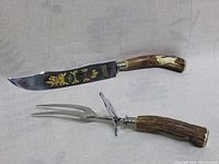 Full view of carving knife and fork showing decorated knife blade and carved wood handles.