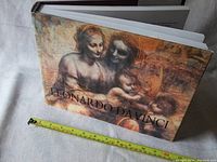 Front cover showing Leonardo Da Vinci artwork and book size with measuring tape for scale.