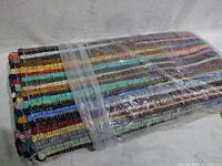 Side view of folded multi-colored handwoven rug wrapped in plastic