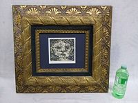 Full front view of framed etching showing size scale with a water bottle.