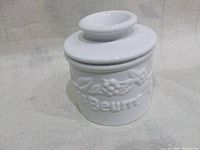 Closed ceramic butter bell crock showing embossed grapevine pattern and 'Beurre' text.