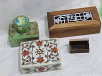 Four vintage trinket boxes on a plain background showing different materials and designs.
