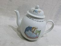 White ceramic teapot with Peter Rabbit illustration and story text, side view showing handle and spout.