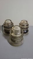 Three Hemingray No.42 glass insulators placed together showing rounded tops and clear glass.