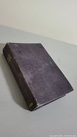 Closed antique Bible with dark hardcover showing wear and age marks.