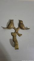 Front view of the solid brass bird hook showing two birds perched on a branch and the hook below.