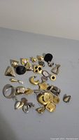 Top view of earrings lot showing multiple gold-tone, silver-tone and black earrings in various geometric and floral shapes