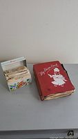 Wide shot of both the large red recipe book titled 'My Recipe Book' and the smaller white recipe box with recipe cut-outs.