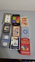 Nine decks of various playing cards assorted by different box designs and styles